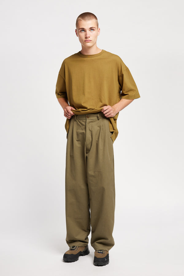 Front view of model wearing the logic pleat pant in Olive. A relaxed cotton trouser with pleated front and tapered leg