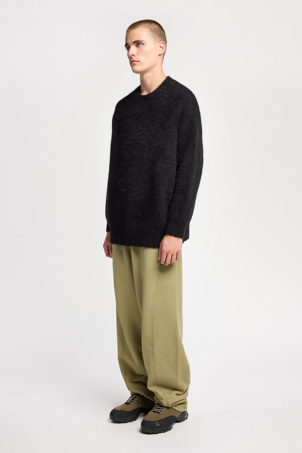 Front angle of Model wearing oversized fluffy knit crew neck sweater in black. 
