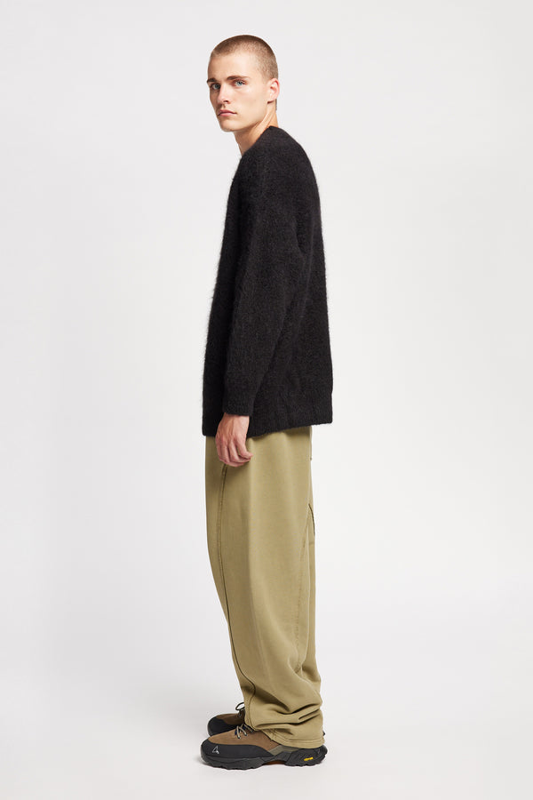 Side of Model wearing oversized fluffy knit crew neck sweater in black. 
