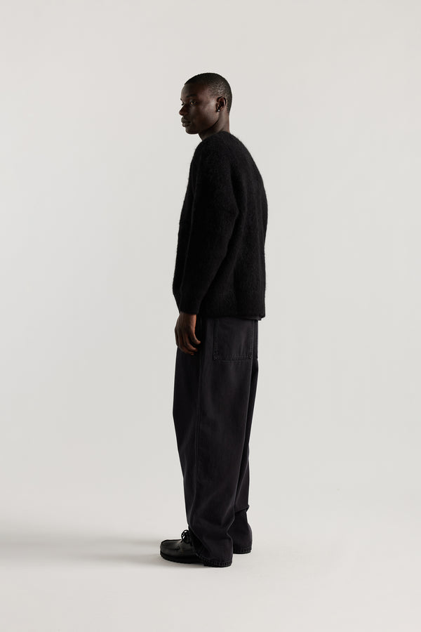 Side of Male Model wearing oversized brushed alpaca blend knit crew neck sweater in Black 