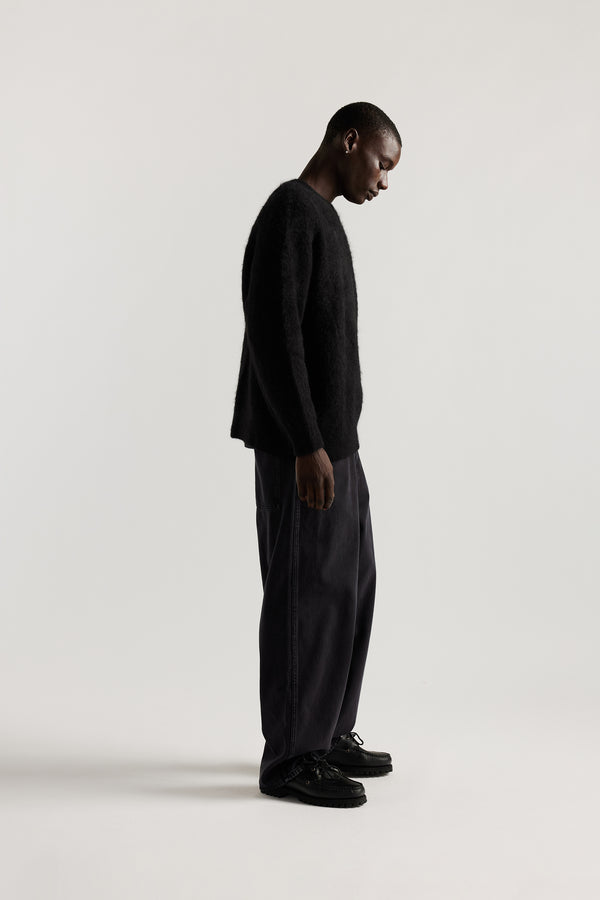 Side of Male Model wearing oversized brushed alpaca blend knit crew neck sweater in Black 