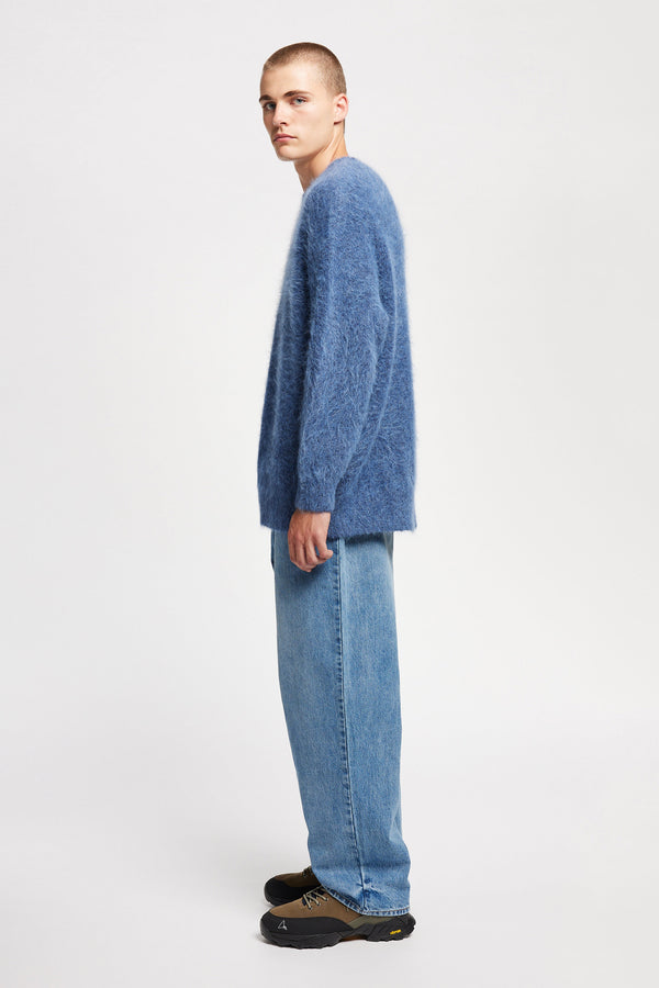Side of Model wearing oversized fluffy knit crew neck sweater in indigo blue. 
