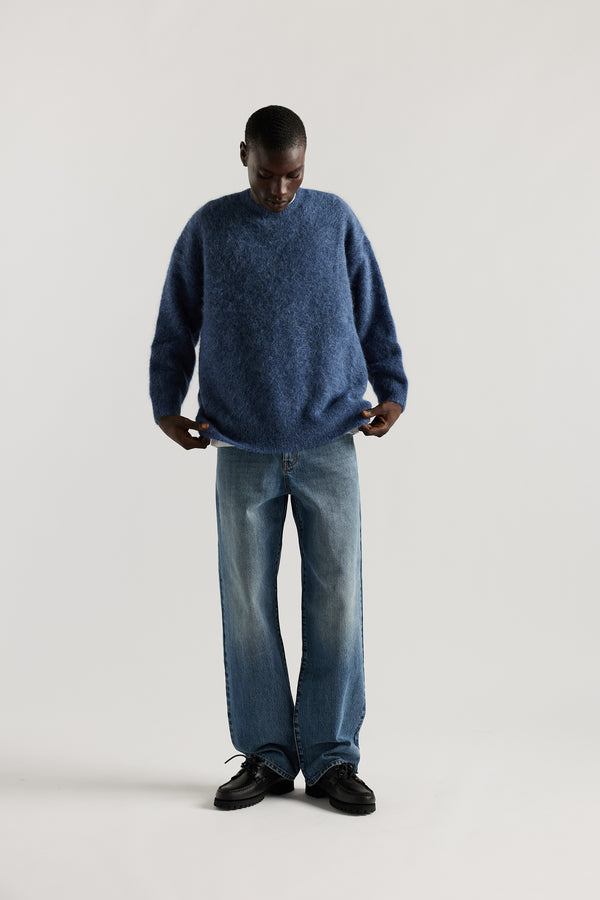 Front of Model wearing oversized fluffy alpaca  knit crew neck sweater in indigo blue. 
