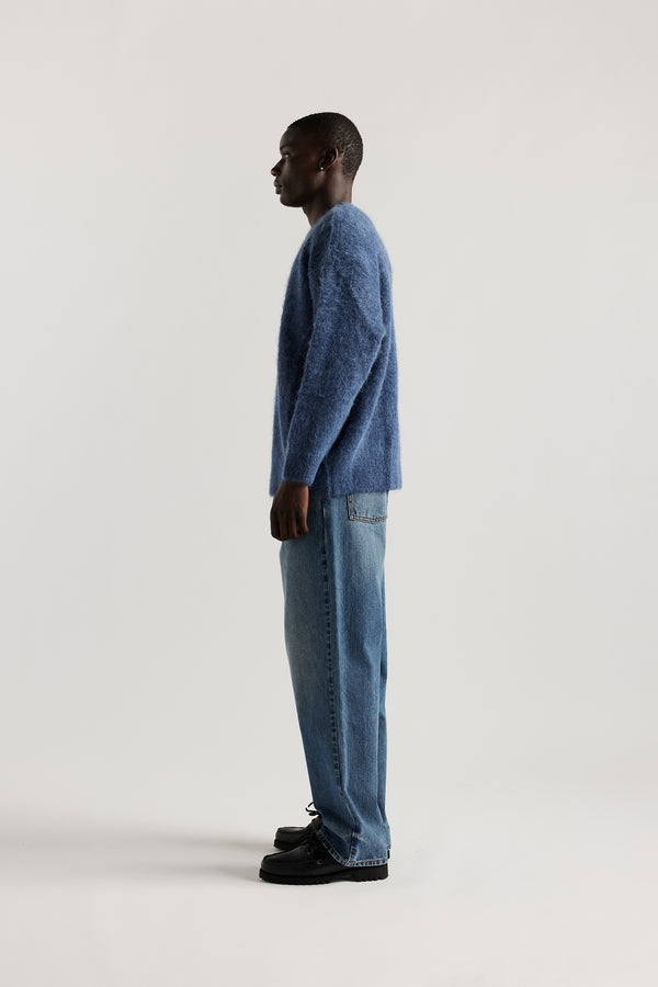 Side of Model wearing oversized fluffy alpaca  knit crew neck sweater in indigo blue. 
