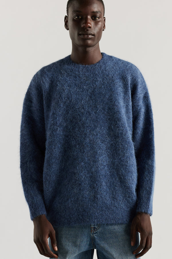 Front of Model wearing oversized fluffy knit crew neck sweater in indigo blue. 
