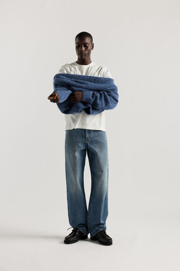 Front of Model wearing oversized fluffy alpaca  knit crew neck sweater in indigo blue. 
