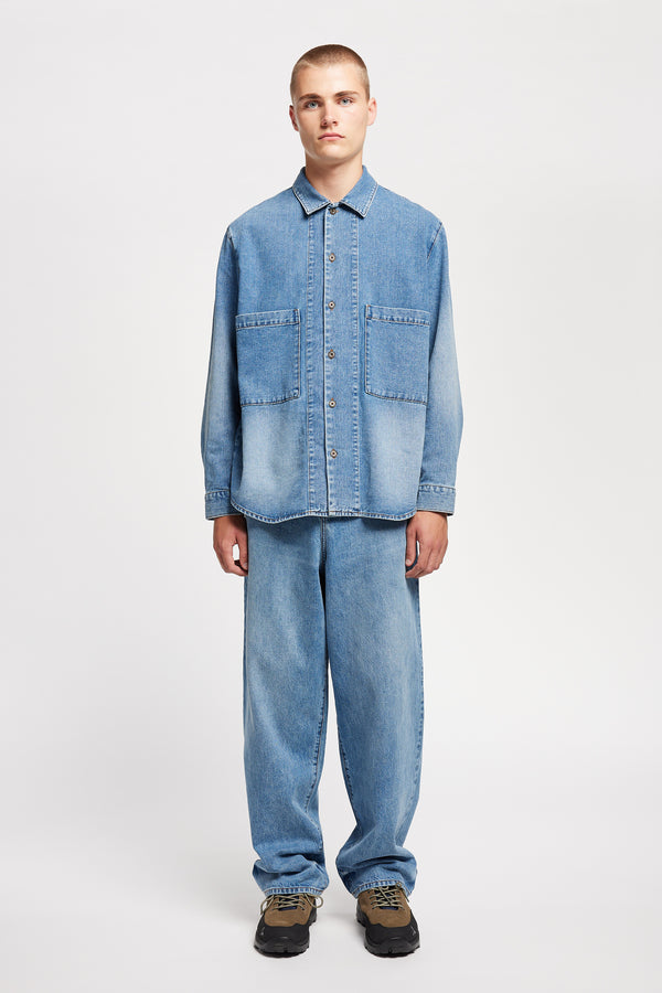 Front view of model wearing the Mascot relaxed fit denim shirt in mid-blue, featuring utility chest pockets.