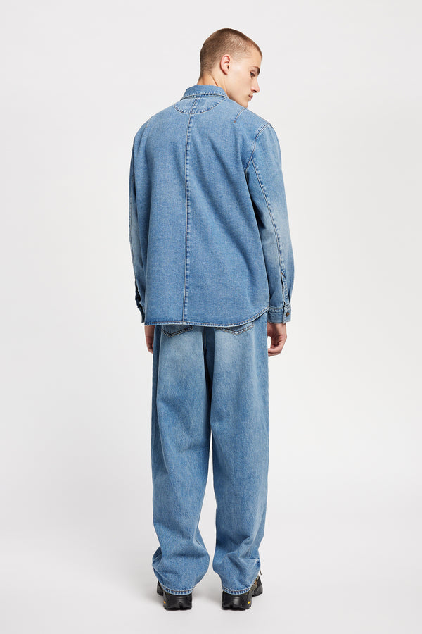 Back view of model wearing the Mascot relaxed fit denim shirt in mid-blue, featuring utility chest pockets.