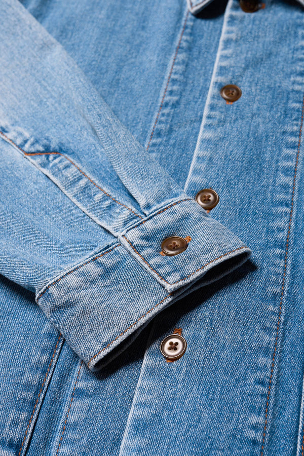 Close up detail cuff and button shot of the Mascot relaxed fit denim shirt in mid-blue, featuring utility chest pockets.