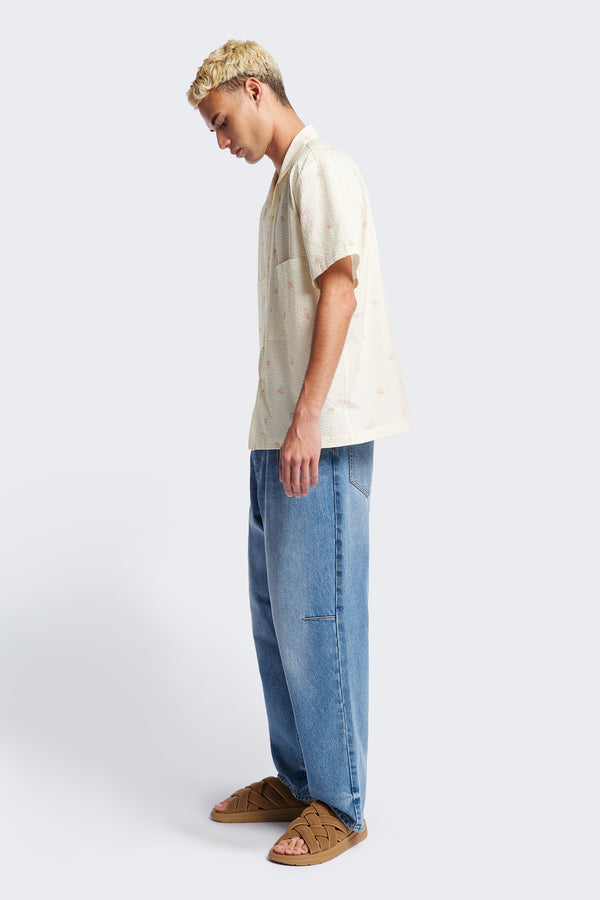 Side of the Mirari in Ecru floral, a relaxed short-sleeve open-collar camp shirt made from soft textured cotton seersucker, offering a laid-back fit. Available in 5 sizes. 