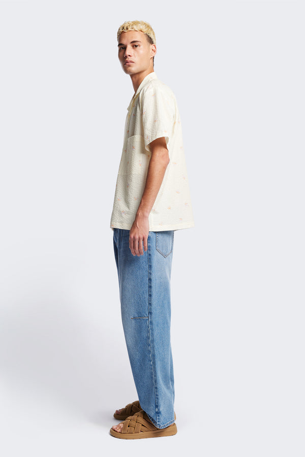 Side of the Mirari in Ecru floral, a relaxed short-sleeve open-collar camp shirt made from soft textured cotton seersucker, offering a laid-back fit. Available in 5 sizes. 