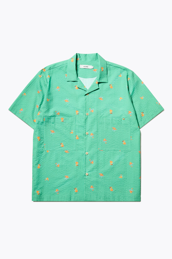 Flat Front of the Mirari in Green floral, a relaxed short-sleeve open-collar camp shirt made from soft textured cotton seersucker, offering a laid-back fit. Available in 5 sizes. 