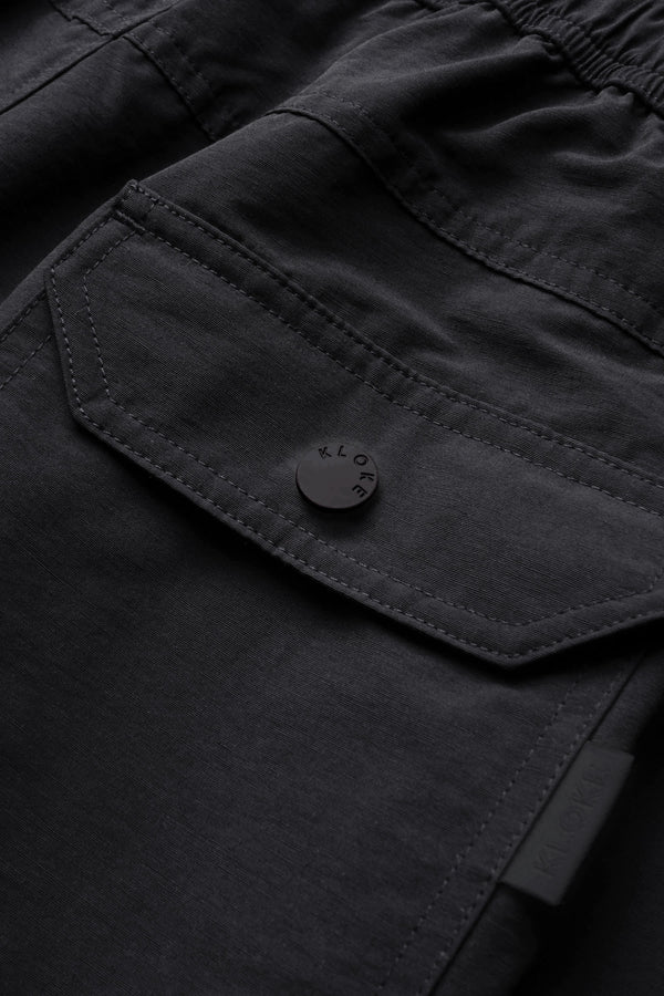 Close up details of The New Wave Short in Black. Swim shorts with elastic drawstring waist, internal mesh support, and front slant pockets. Available in 5 sizes.