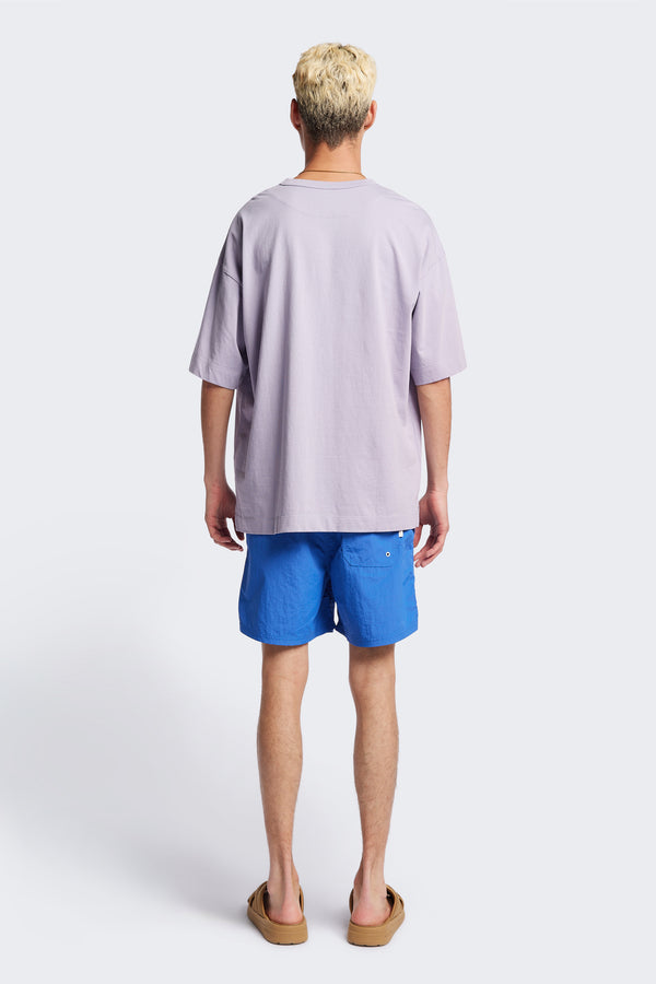 Back of The New Wave Short in Lapis Blue. Swim shorts with elastic drawstring waist, internal mesh support, and front slant pockets. Available in 5 sizes.