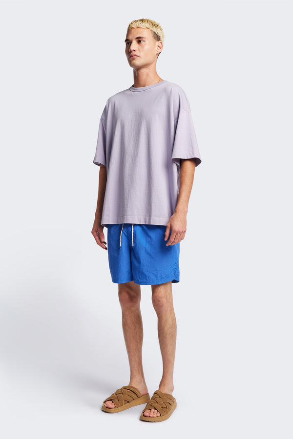 The New Wave Short in Lapis Blue. Swim shorts with elastic drawstring waist, internal mesh support, and front slant pockets. Available in 5 sizes.