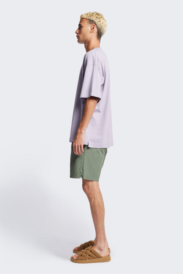 Side of The New Wave Short in Fatigue Green. Swim shorts with elastic drawstring waist, internal mesh support, and front slant pockets. Available in 5 sizes.