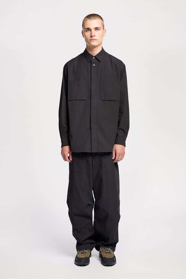 Front of the Model wearing the Offset Shirt in a black heavyweight cotton, featuring a relaxed fit and utility chest pockets.