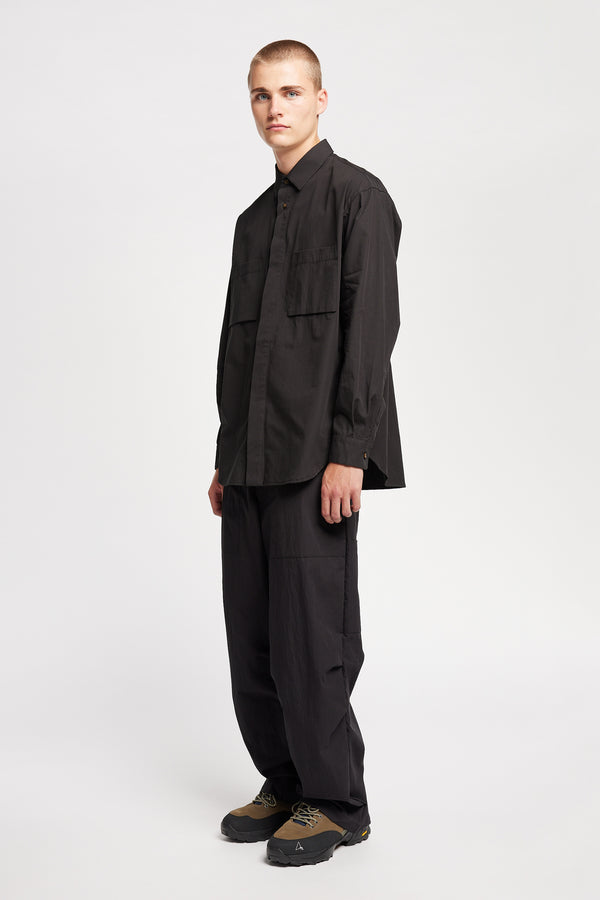 Front angle of the Model wearing the Offset Shirt in a black heavyweight cotton, featuring a relaxed fit and utility chest pockets.