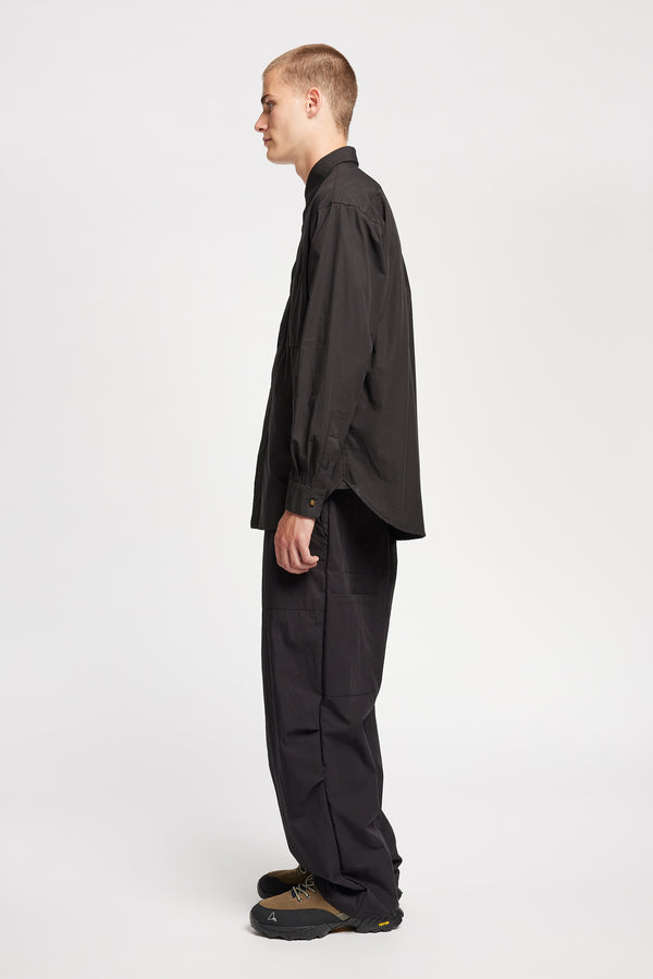Side of the Model wearing the Offset Shirt in a black heavyweight cotton, featuring a relaxed fit and utility chest pockets.