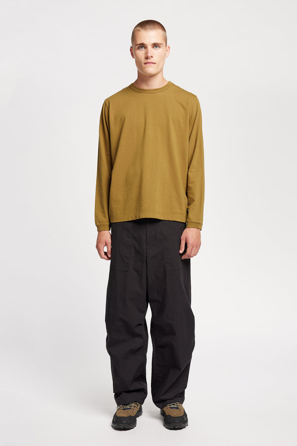 Front view of model wearing Output Pant in black, a relaxed fit with wide tapered leg and clean patch pockets 