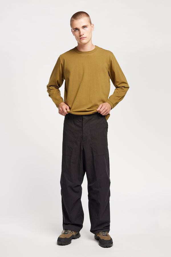 Front view of model wearing Output Pant in black, a relaxed fit with wide tapered leg and clean patch pockets 