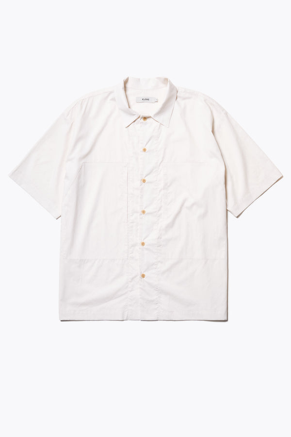 Flat Front of the Ecru Perisi shirt in lightweight micro ripstop cotton, featuring deep double patch map pockets at the chest, buttoned-up design, and a relaxed straight hemline. Available in sizes XS, S, M, L, and XL.