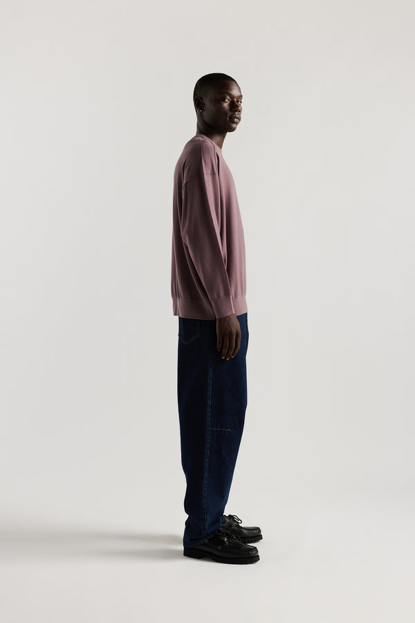Side of Male model wearing mauve refined merino wool crew neck jumper with relaxed fit, dropped shoulders, exposed seam detailing.