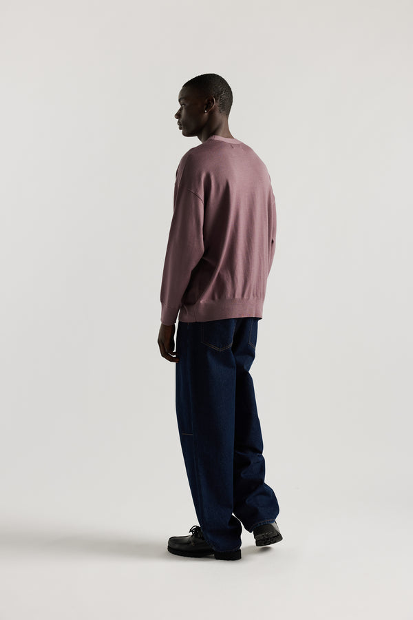 Back of Male model wearing mauve refined merino wool crew neck jumper with relaxed fit, dropped shoulders, exposed seam detailing.
