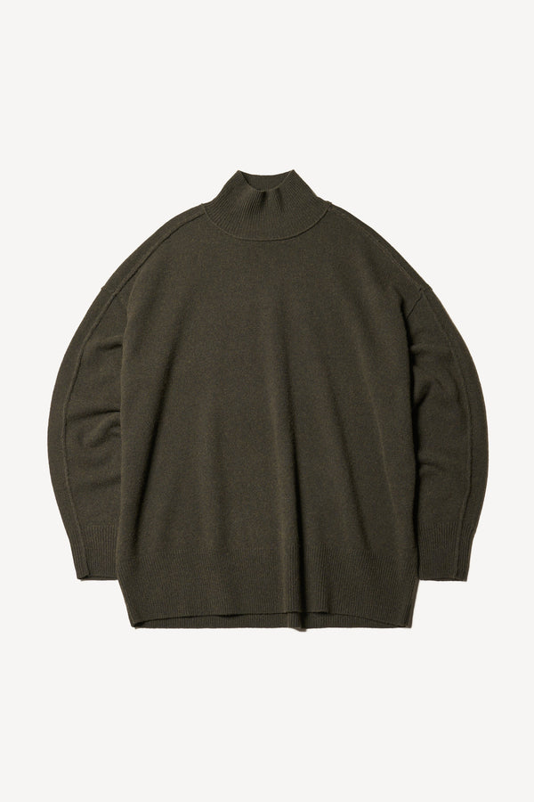 Flat Front of mock neck merino wool fisherman sweater with exposed seams in Darkest Green. 