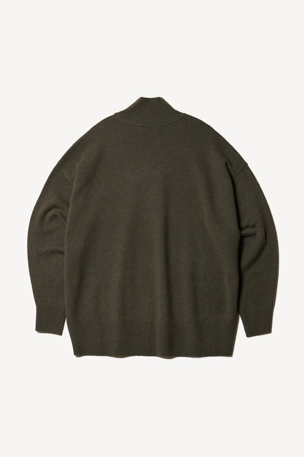 Flat Back of mock neck merino wool fisherman sweater with exposed seams in Darkest Green. 