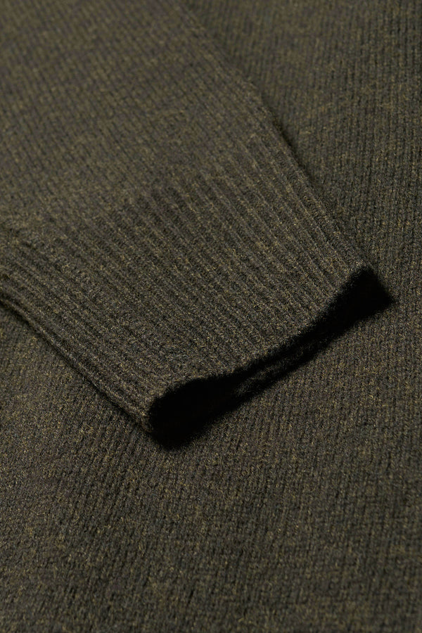 Close up fabric detail of the Prism mock neck merino wool fisherman sweater with exposed seams in Darkest Green. 