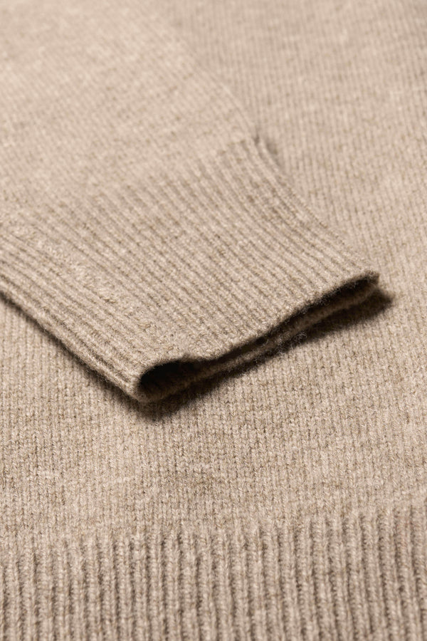 Close up fabric detail of the Prism mock neck merino wool fisherman sweater with exposed seams in Taupe. 