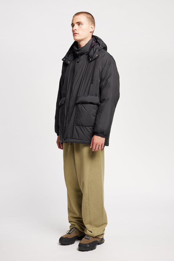 Front view of model the  Men’s Prospect Down Puffa a technical jacket with removable hood and utility pockets, made from recycled nylon. In Black