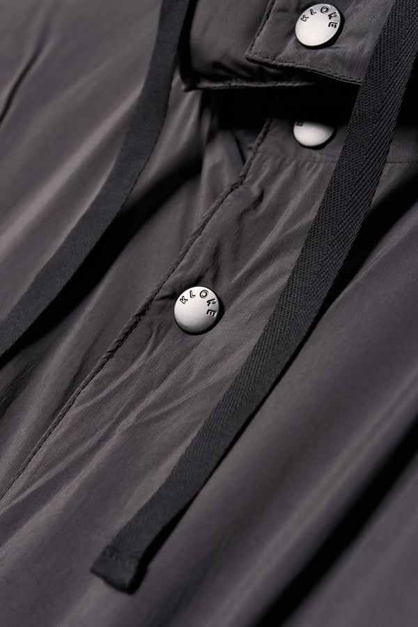 Close up button detail shot of the  Men’s Prospect Down Puffa a technical jacket with removable hood and utility pockets, made from recycled nylon. In Black
