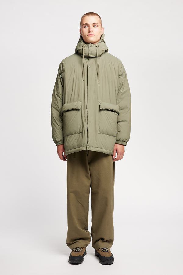 Front view of model the  Men’s Prospect Down Puffa a technical jacket with removable hood and utility pockets, made from recycled nylon. In Dusty Olive Green 