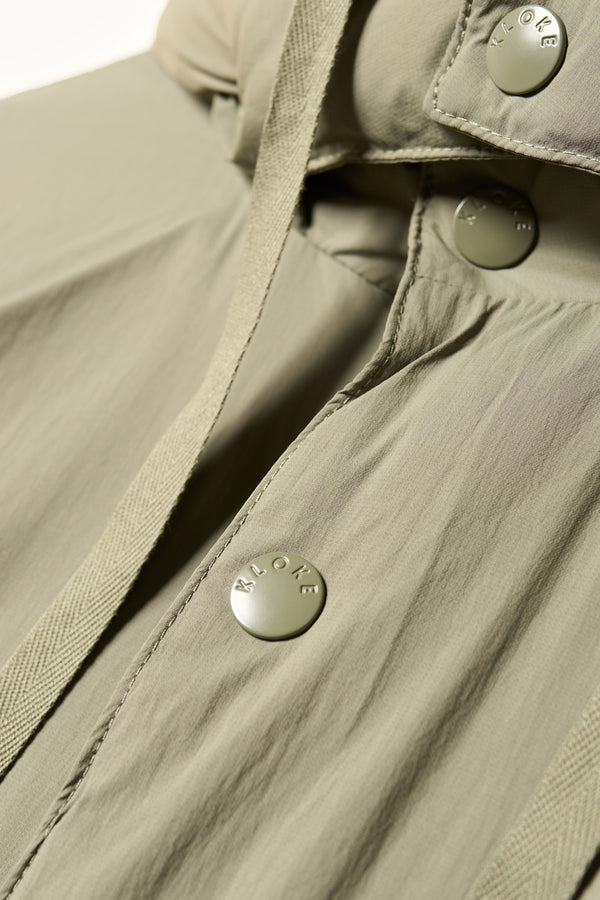 Close up button detail shot of the  Men’s Prospect Down Puffa a technical jacket with removable hood and utility pockets, made from recycled nylon. In Dusty Olive Green 