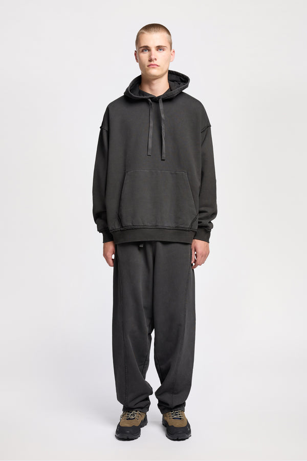 Front of model wearing oversized pigment-dyed hoodie with dropped shoulders and kangaroo pocket in jet black