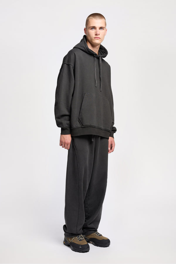 Front of model wearing oversized pigment-dyed hoodie with dropped shoulders and kangaroo pocket in jet black
