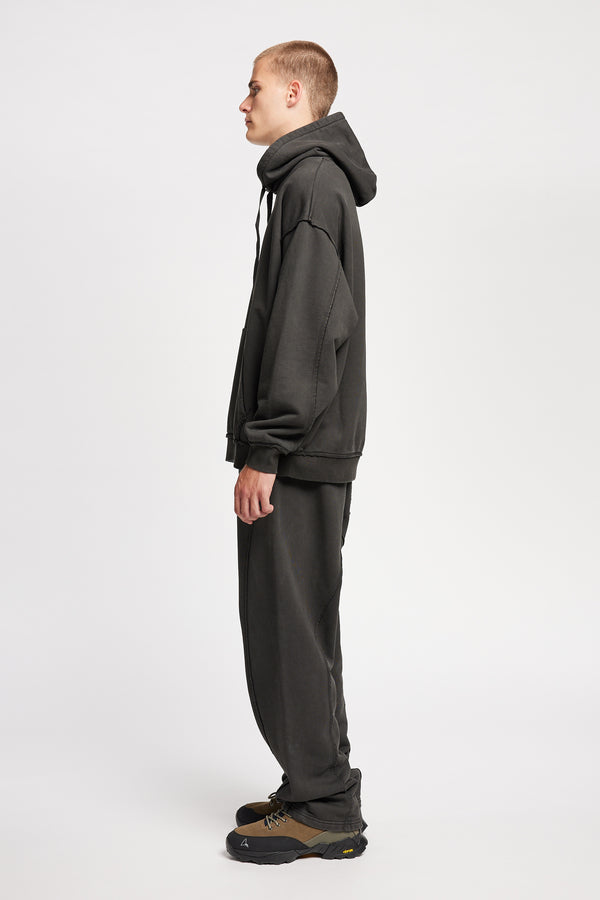 Side of model wearing oversized pigment-dyed hoodie with dropped shoulders and kangaroo pocket in jet black