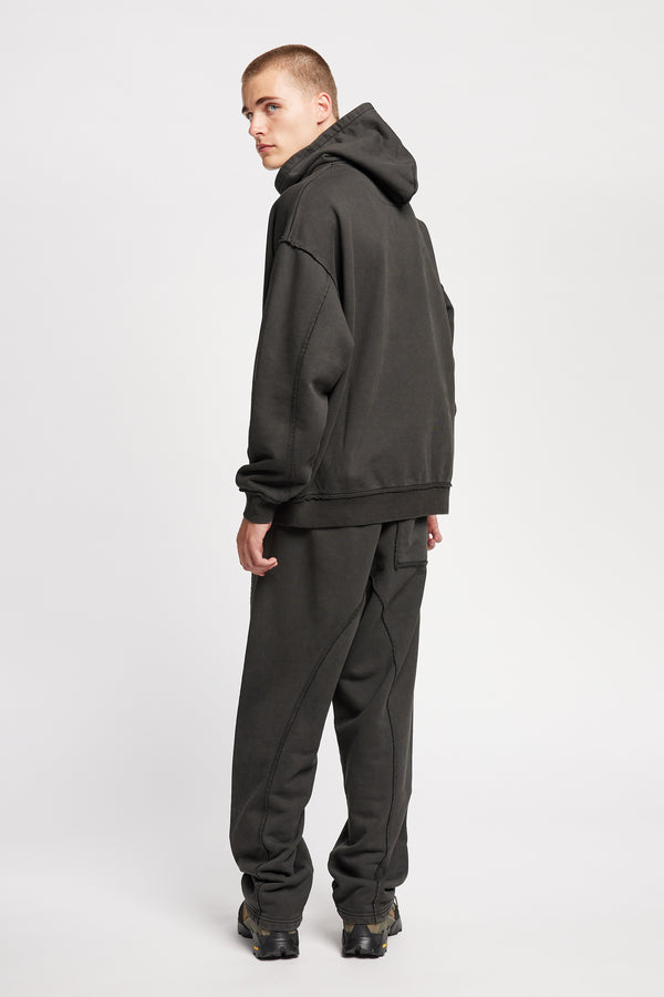 Back of model wearing oversized pigment-dyed hoodie with dropped shoulders and kangaroo pocket in jet black