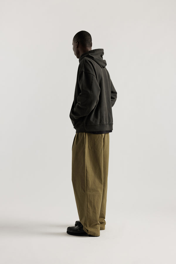 Side Back of model wearing oversized pigment-dyed hoodie with dropped shoulders and kangaroo pocket in jet black