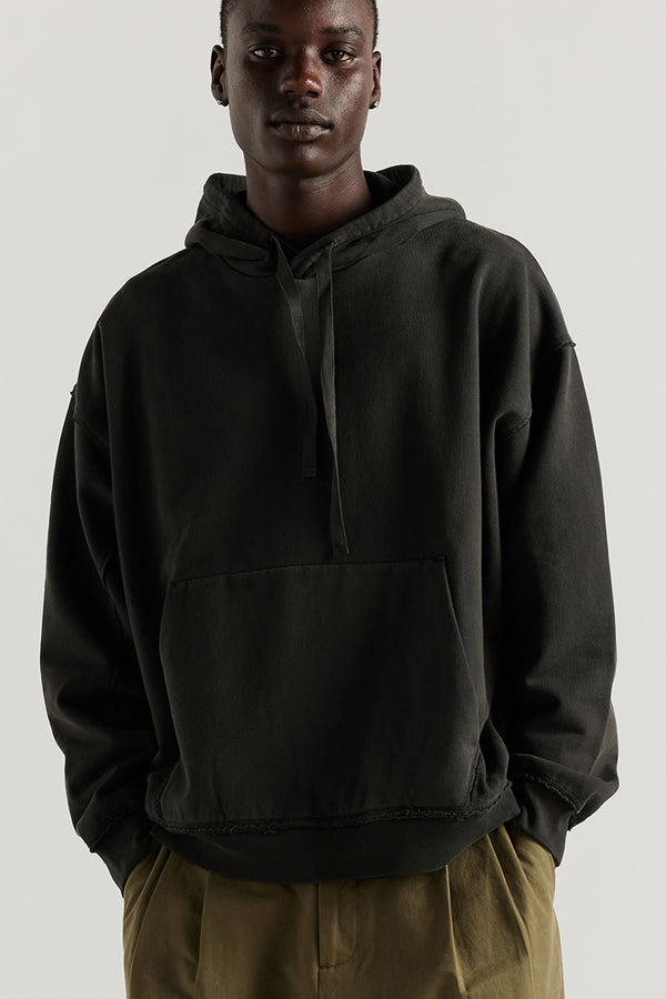 Front of model wearing oversized pigment-dyed hoodie with dropped shoulders and kangaroo pocket in jet black