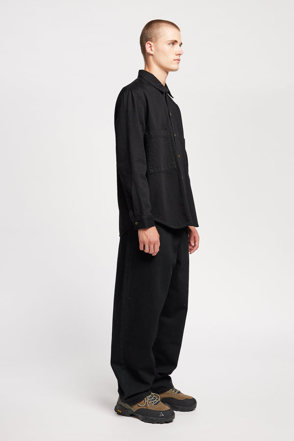 Front view of model in the renew jean, a relaxed loose-fit straight style in premium Japanese denim, shown in black with five-pocket design and custom branded hardware.
