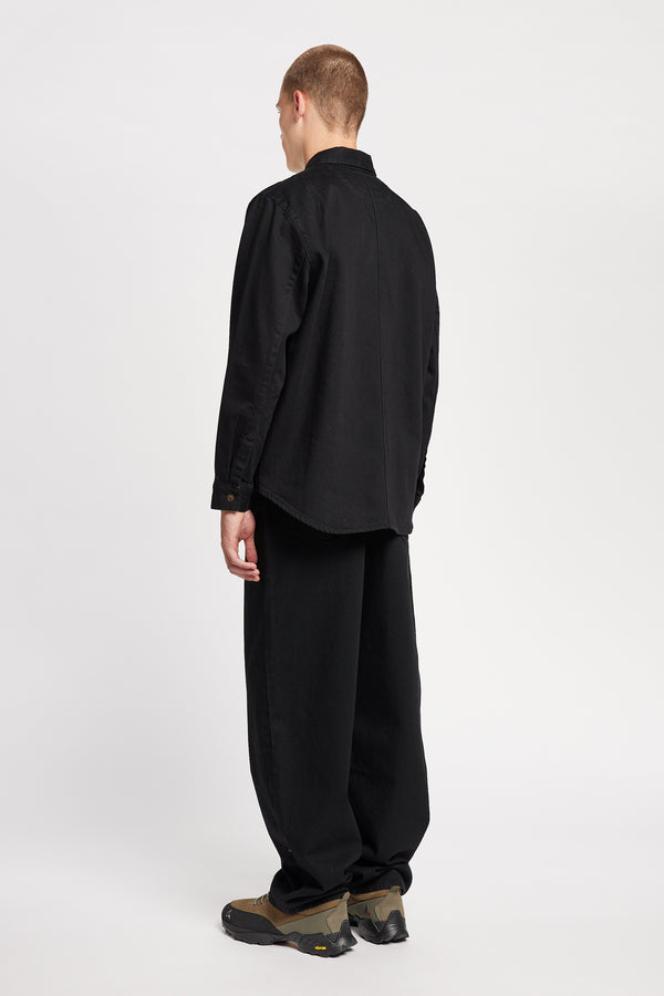 Back view of model in the renew jean, a relaxed loose-fit straight style in premium Japanese denim, shown in black with five-pocket design and custom branded hardware.