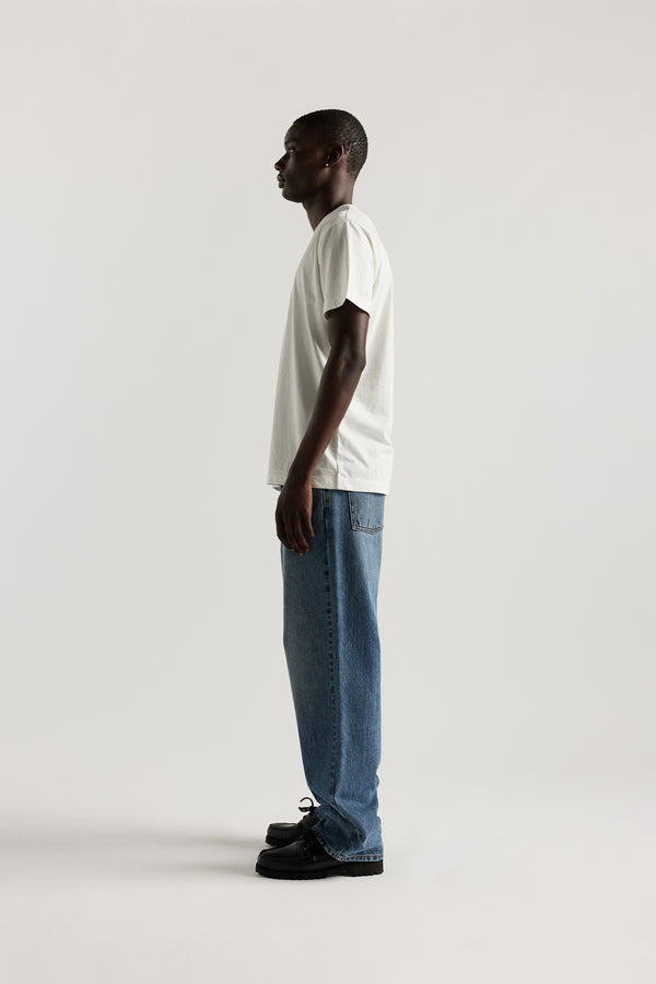 Side view of model in the renew jean, a relaxed loose-fit straight style in premium Japanese denim, shown in mid-blue fade.
