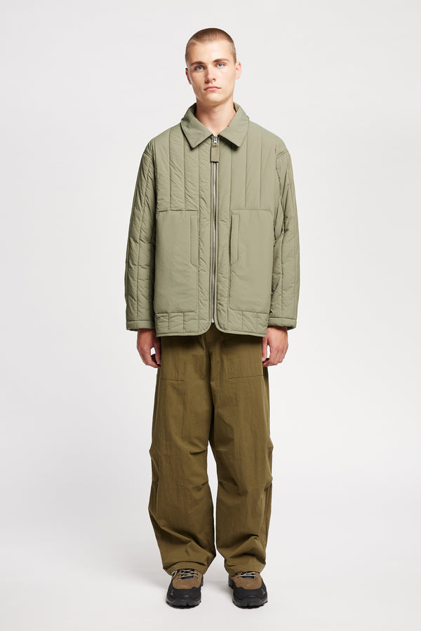 Front view of model wearing the response quilted military field jacket with structured collar and concealed zip in dusty olive green