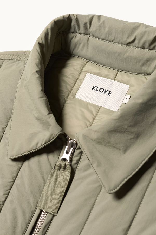 Close up Collar detail shot of the response quilted military field jacket with structured collar and concealed zip in dusty olive green