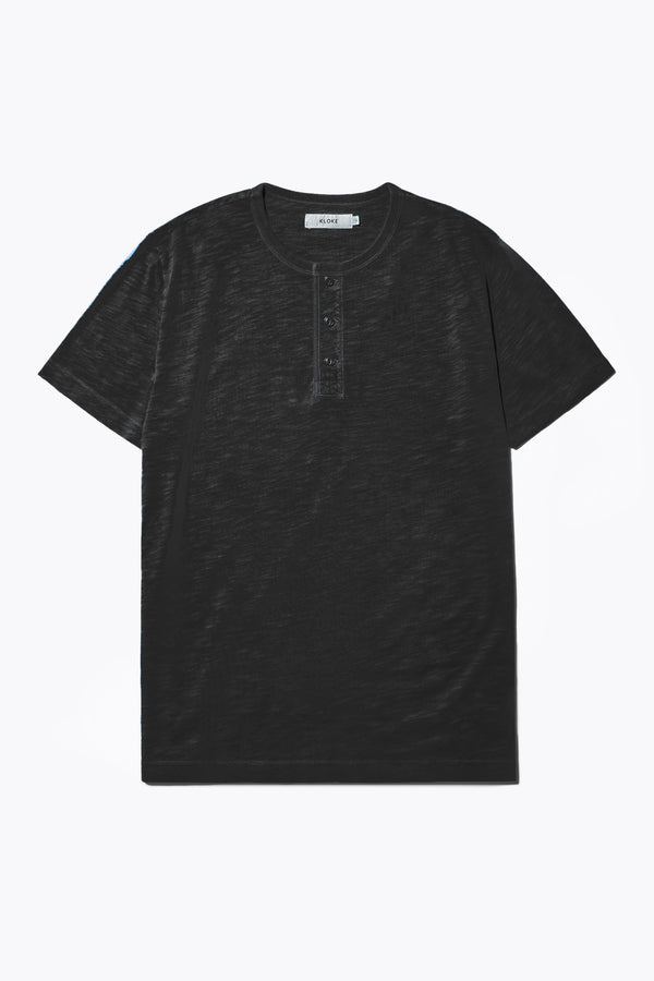 The Stratus Henley T-shirt in Vintage Black. Garment-dyed in soft cotton jersey with three-button placket and coverstitched hems. Available in 5 sizes. 