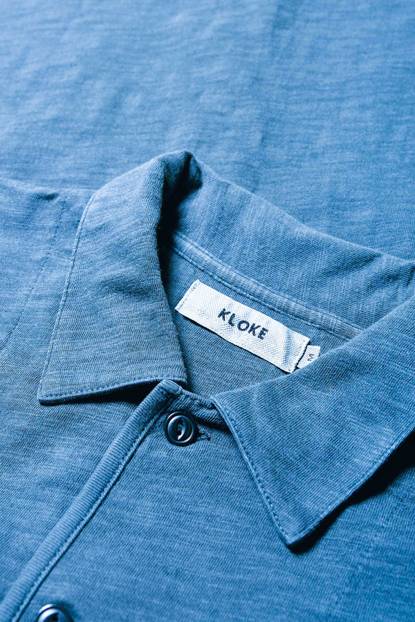 Close up collar detail of The Tectonic Shirt in blue, a classic boxy fit T-Shirt made from 100% cotton garment dyed jersey with a reinforced back yoke. Available in 5 sizes. 