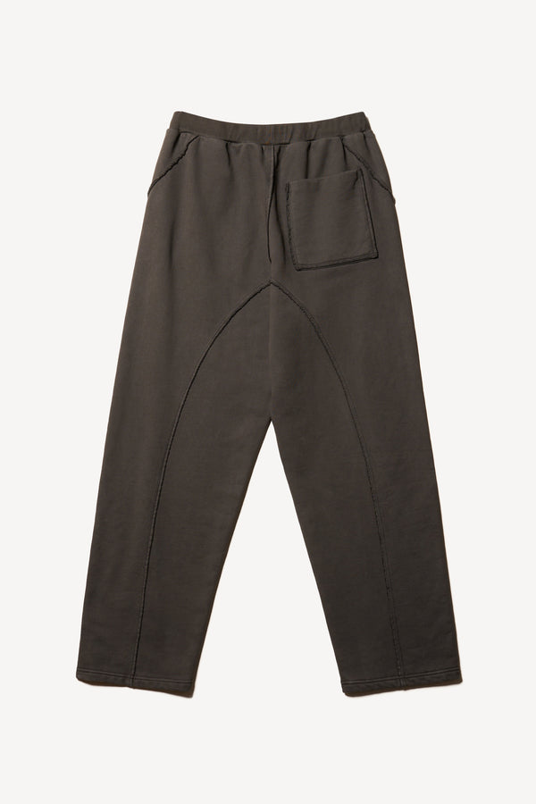 Flat Back of relaxed tapered fleece pants in Black pigment-dyed cotton with curved seam detailing and elastic waistband